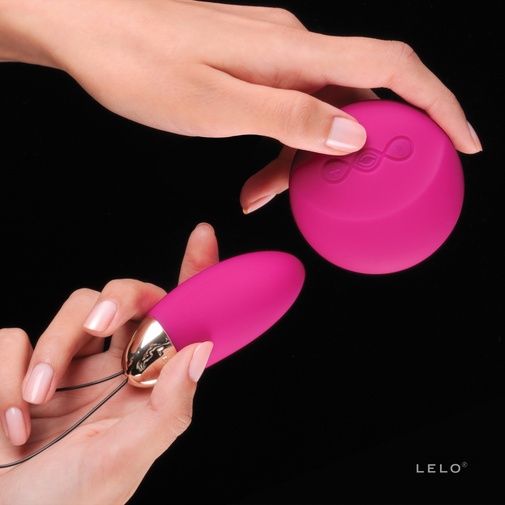 Detail na veľkosť vibračného vajíčka Lelo Lyla 2  s ovládačom v ruke.