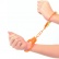 Pevné kovové putá neónovo oranžovej farby s bezpečnostou poistkou a dvoma kľúčikmi nasadené na rukách.